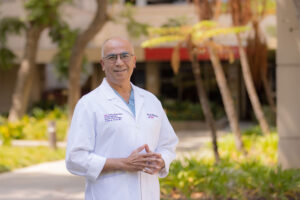 A portrait of Dr. Uttam Sinha standing outside in a white medical coat.